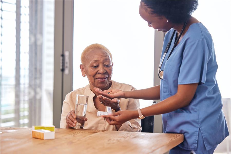 Caregiver helping an older woman with medication at home
