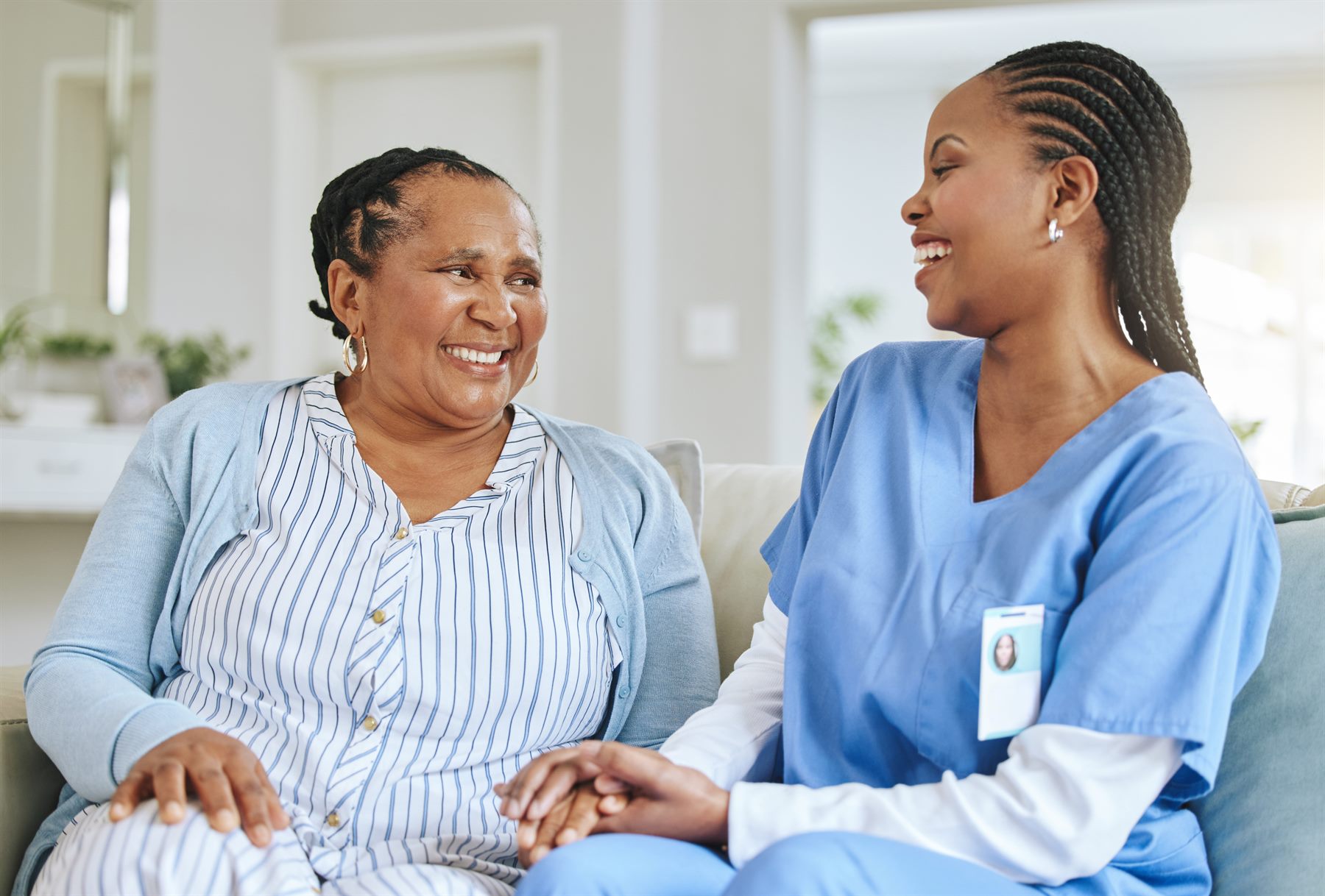 Nurse and senior woman laughing together during home care