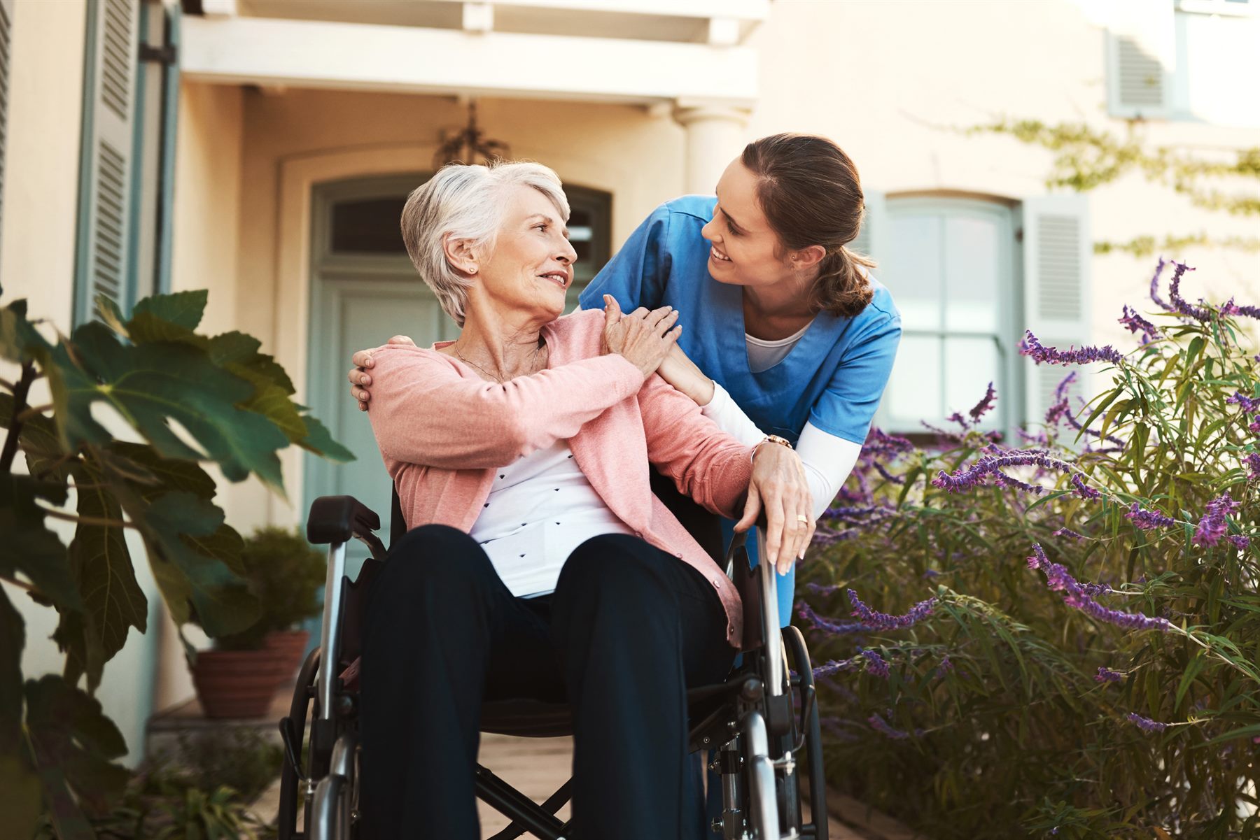 Caregiver talking with a senior woman in a wheelchair outdoors